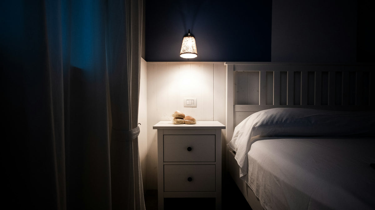 Bedside lamp glowing next to a made bed