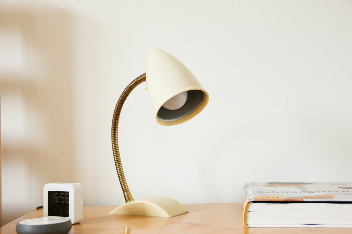 Cream and brass gooseneck desk lamp on a wooden desk